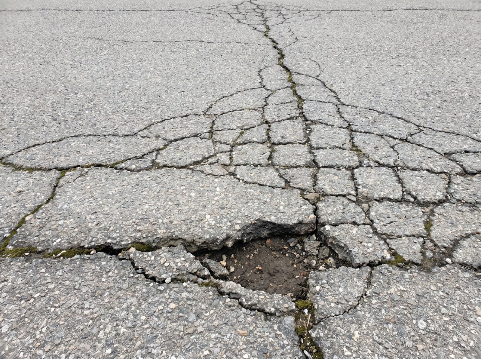 Network of cracks in weathered gray asphalt