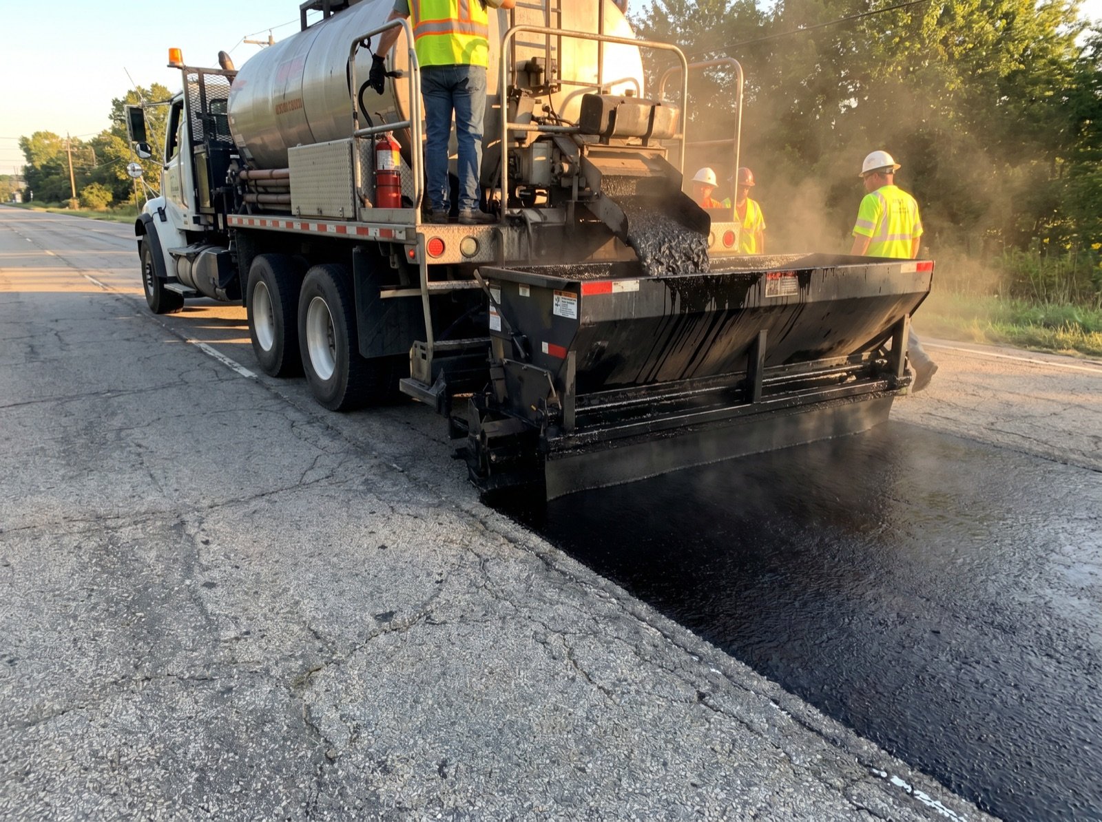 Microsurfacing machine spreading polymer-modified slurry over asphalt