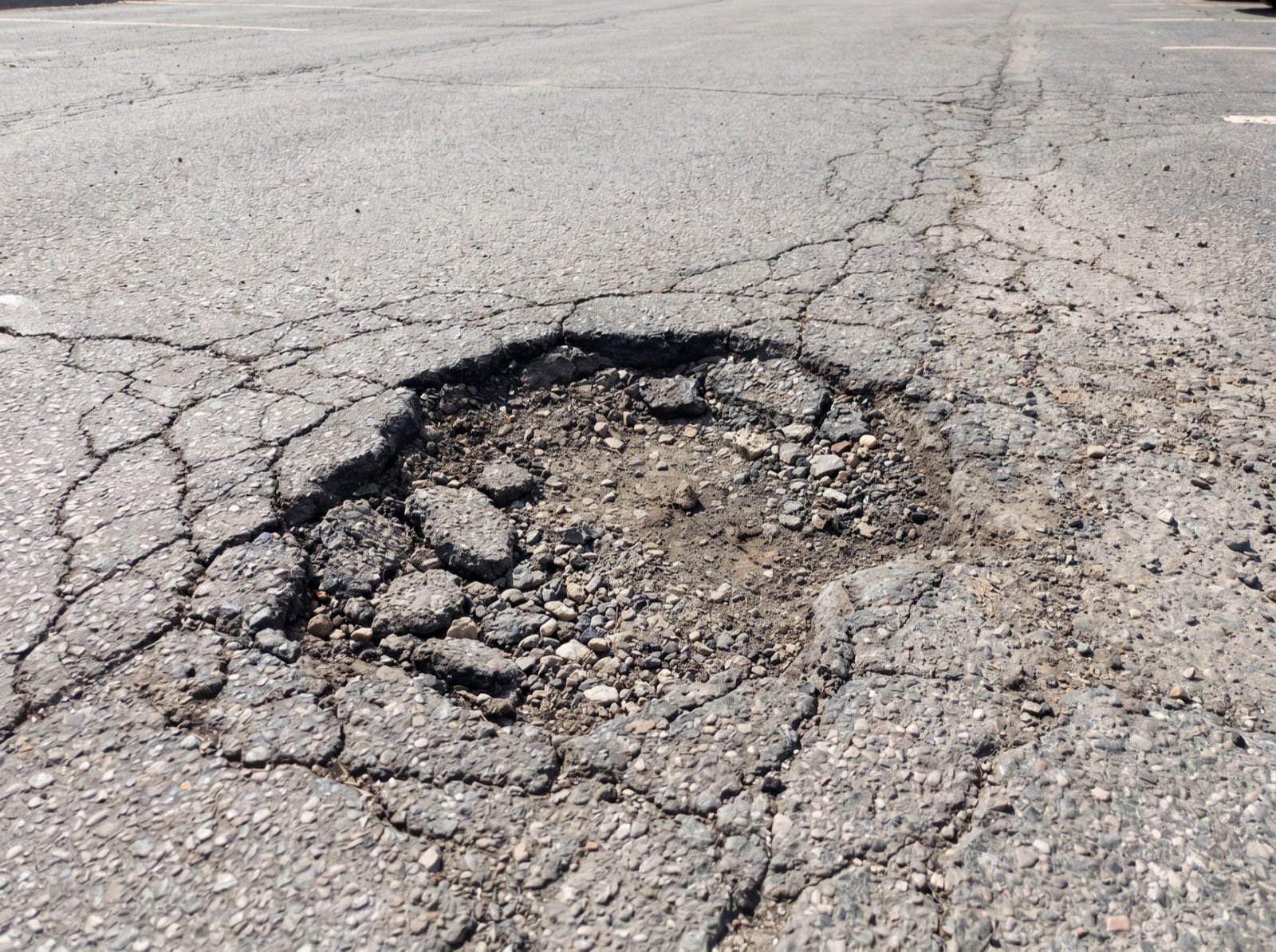 Pothole and failed broken asphalt in a parking lot