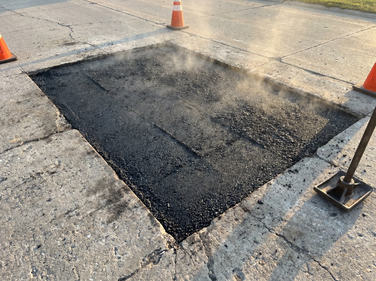 Fresh hot-mix asphalt patch compacted into older pavement